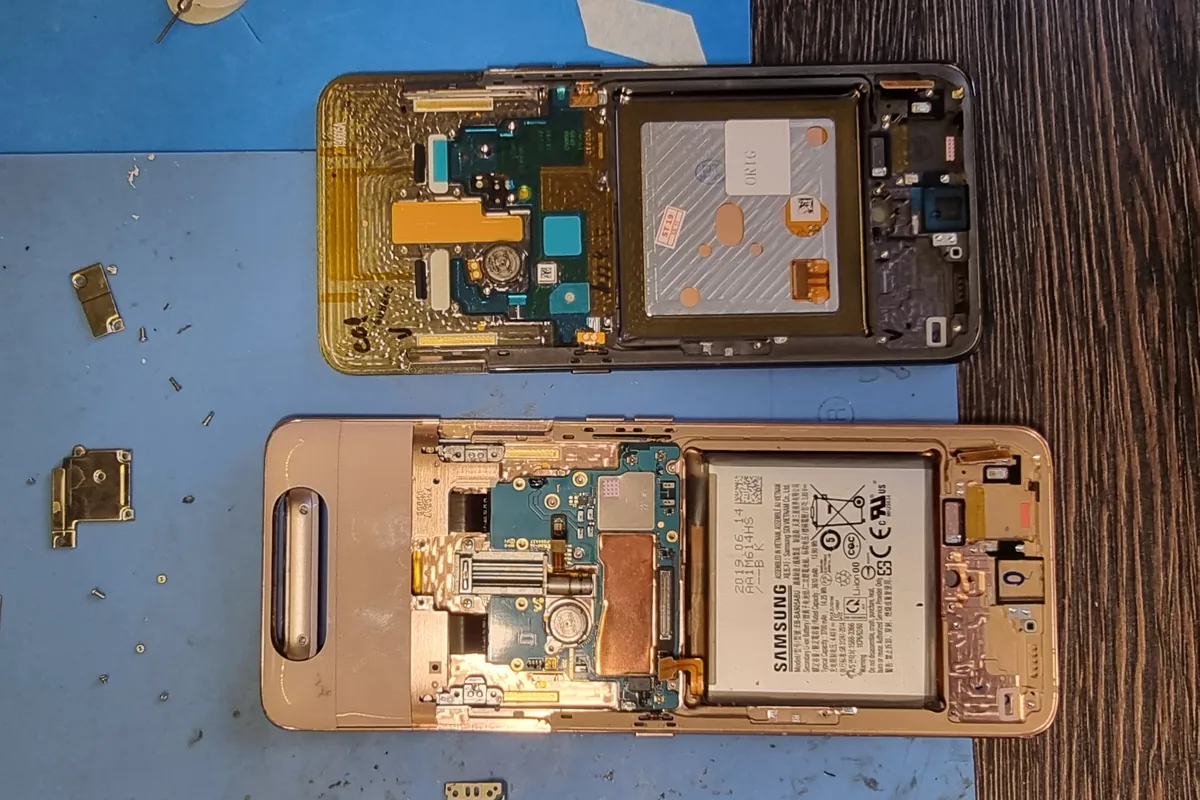 Два частично разобранных смартфона Samsung на рабочем коврике: видны платы, шлейфы и модули камер
