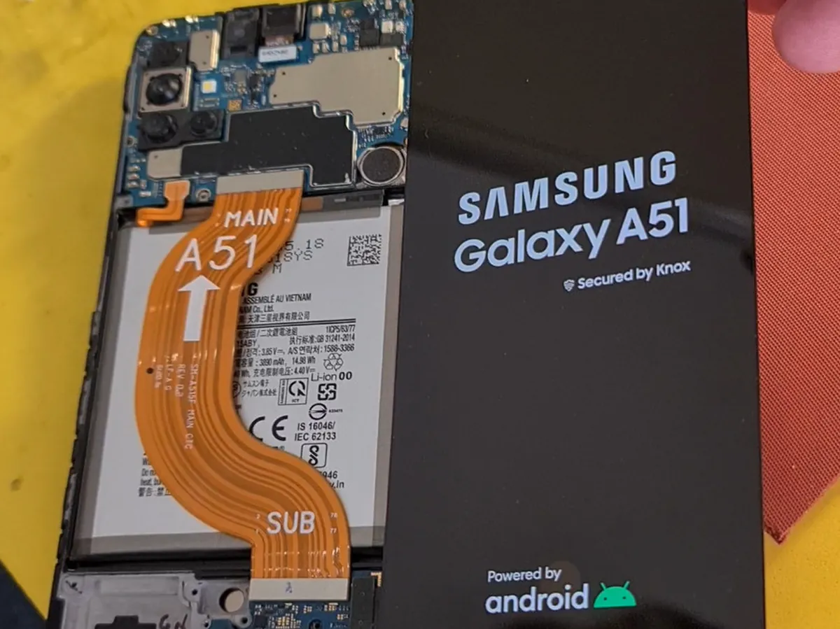 Разобранный смартфон Samsung на столе мастера: снята задняя крышка, видны плата, аккумулятор и шлейфы
