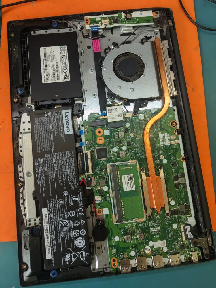 Ноутбук Lenovo со снятой нижней крышкой: материнская плата, аккумулятор, SSD, вентилятор с медной трубкой и два динамика в углах корпуса