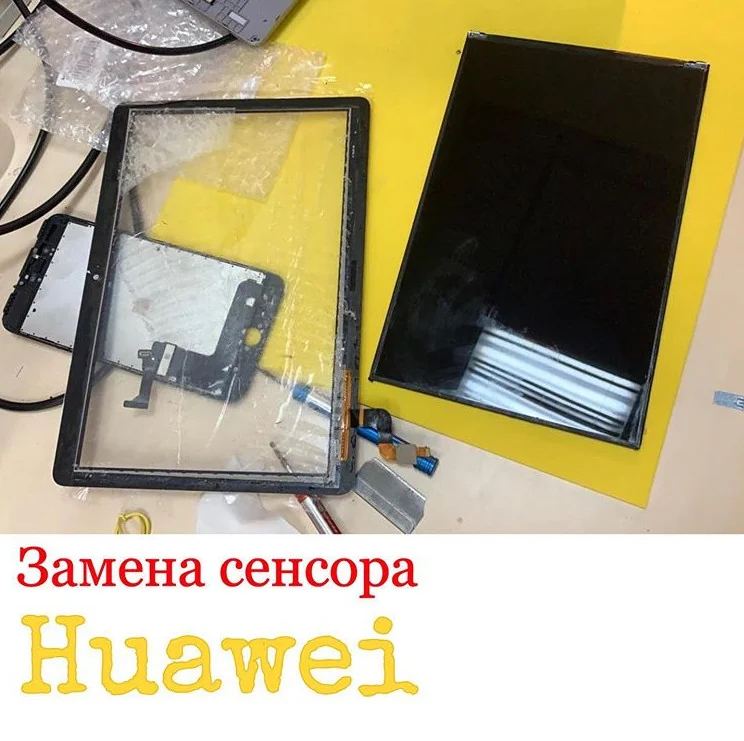 Снятый сенсор планшета Huawei с трещиной лежит на столе рядом с дисплейной матрицей, к которой он был приклеен