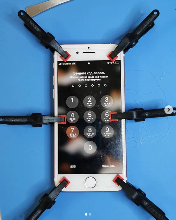 iPhone с новым дисплеем зажат по периметру зажимами на синем коврике, открыт ввод код-пароля.