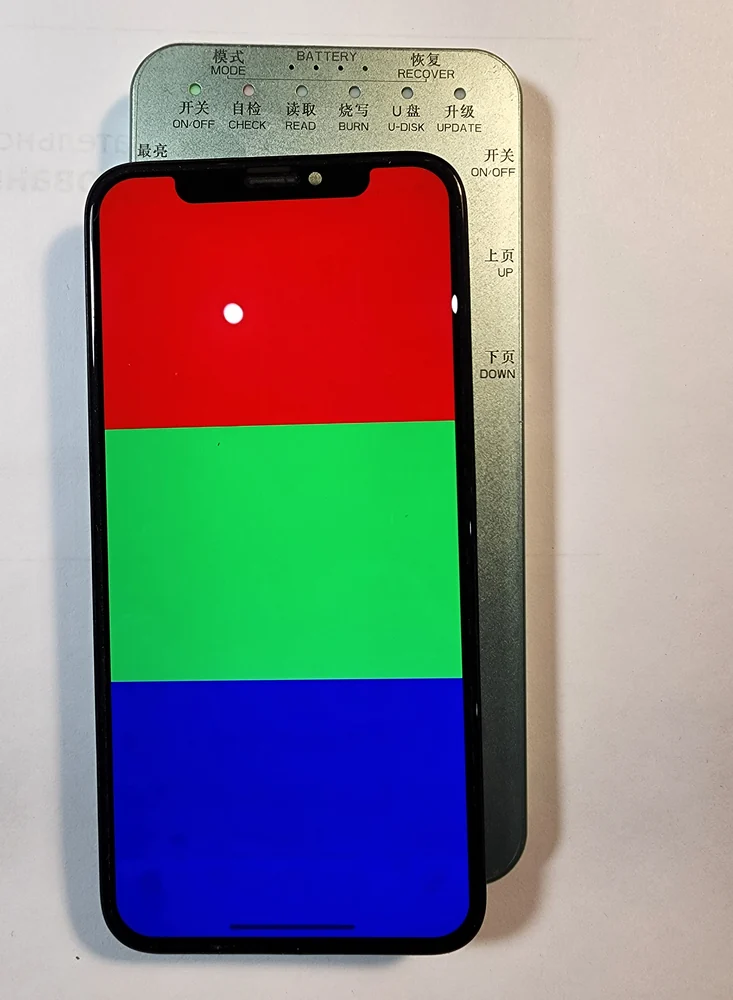 Дисплейный модуль iPhone лежит на металлическом тестере дисплеев с кнопками режимов, экран разделён горизонтально на три поля: красное, зелёное, синее.